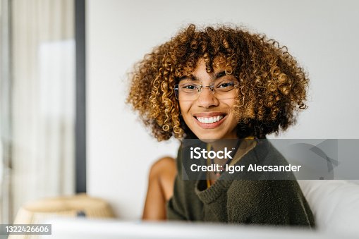 istock Curly haired woman smiling at home 1322426606