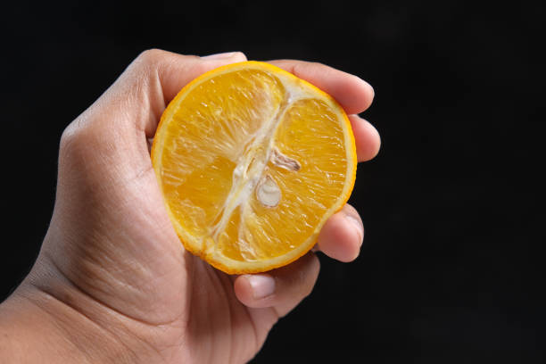 istock hand holding slice of orange fruit isolated on black 1322428463