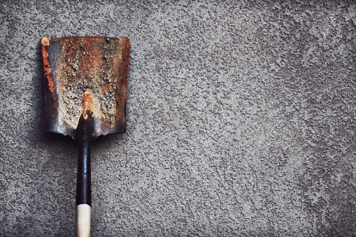 Old shovel against gray stucco wall outdoors