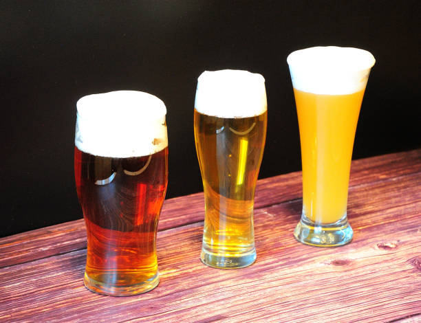 istock Three different glasses with red, light and wheat beer stand in rad on a wooden table. 1322432136