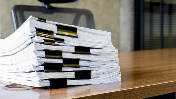 istock Document, Paper, File.Piles of papers placed on a dark wooden table. 1322432271