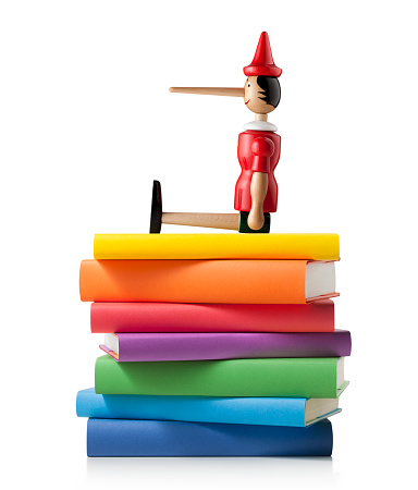 Pinocchio on stack of colored books isolated on white background.
