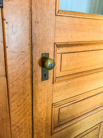 A front view image of a newer metal doorknob on an old wooden grey door.