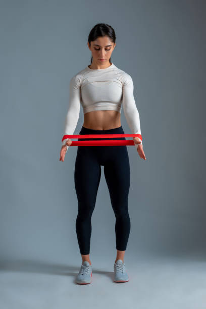 girl doing arm exercises with resistance band on grey background - body building determination deltoid wellbeing imagens e fotografias de stock