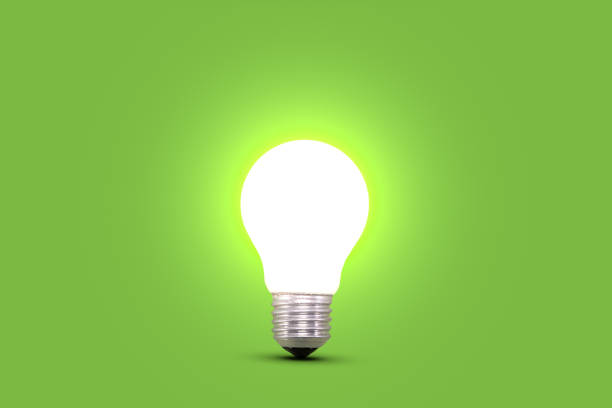 Glowing light bulb isolated on green. One illuminated energy saving light bulb on green background. Side view. Glowing lamp bulb. Concept for ideas, innovation and savings. light bulb photos stock pictures, royalty-free photos & images