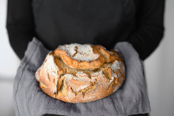 istock Rustic wholegrain sourdough bread, hands holding fresh loaf 1322445162