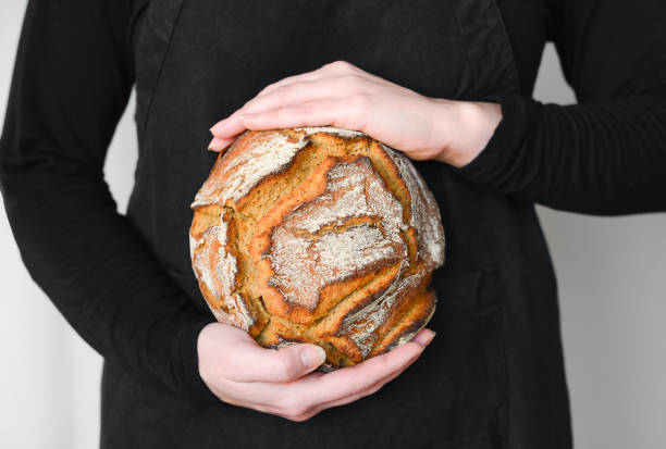 istock Rustic wholegrain sourdough bread, hands holding fresh loaf 1322445169