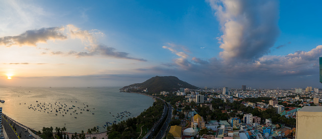 Panoramic coastal Vung Tau view from above, with waves, coastline, streets, coconut trees and Tao Phung mountain in Vietnam. Long exposure photography at dawn.