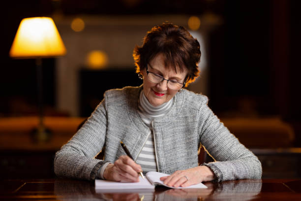 istock Woman sitting at a desk writing in a book 1322445406