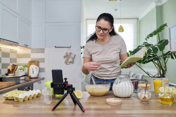 istock Woman preparing apple pie at home in kitchen, talking online using video call 1322445453