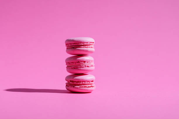 istock Three pink macaroons with pink filling on pink background 1322445534