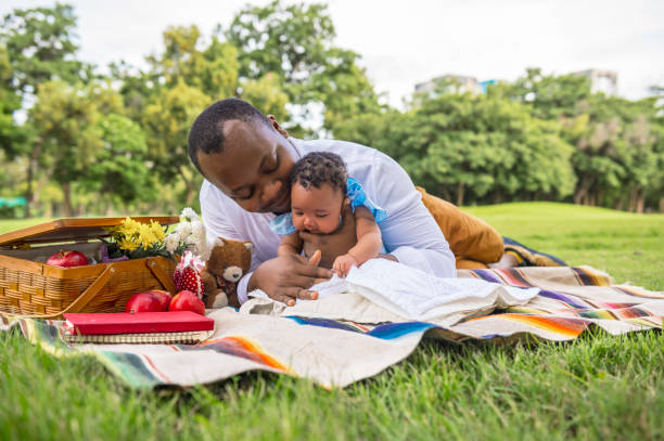 In the park, a father is caring for his infant child. stock photo