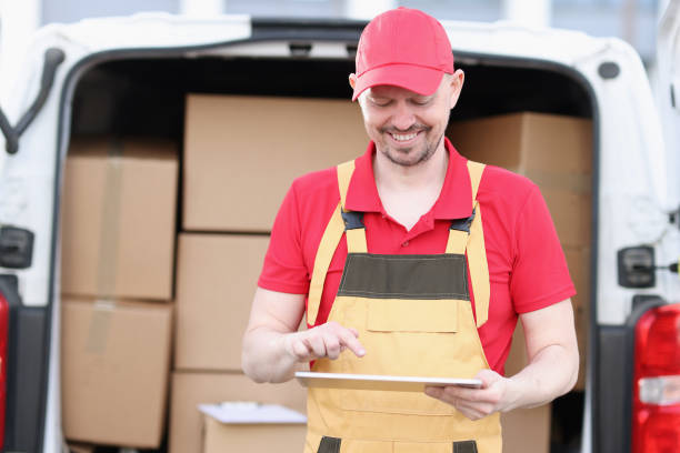 istock Cute caucasian postman in suit and cap checks mailboxes with tablet device in his hands 1322449947