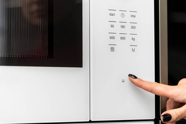 istock Female pushes button on microwave oven close up 1322451111