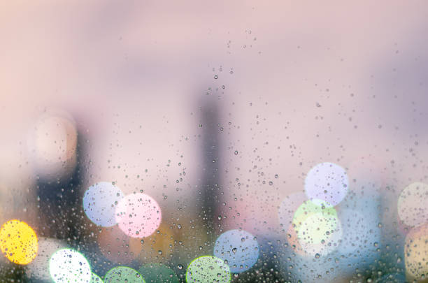 istock Rain drop on glass window in monsoon season with colorful bokeh light 1322451240