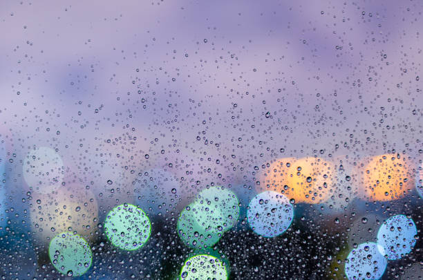 istock Rain drop on glass window in monsoon season with colorful bokeh light 1322451241