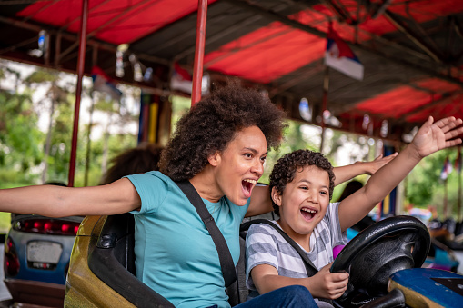 Mother and Son of African-American Ethnicity are Spending a Wonderful Day While Driving in Bumper Car in Luna Park.