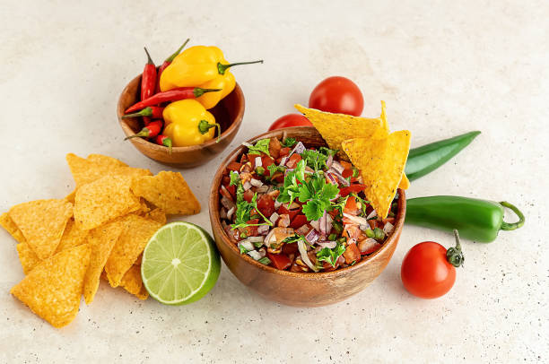 istock Mexican appetizer Pico de Gallo in a bowl and ingredients on the table. 1322457688
