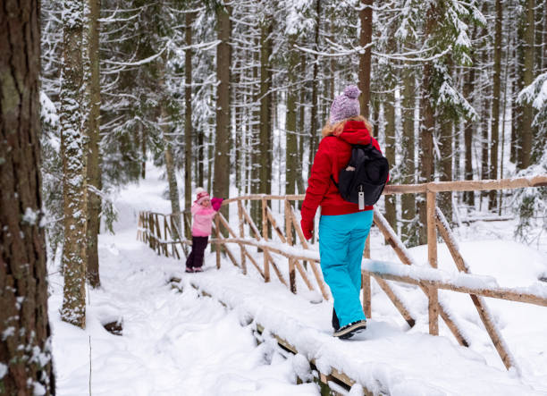 eine kaukasische familie, eine 40-jährige frau und eine tochter von 5 jahren, wandern in einem winterwald, einem wanderweg. - child winter snow 4 5 years stock-fotos und bilder