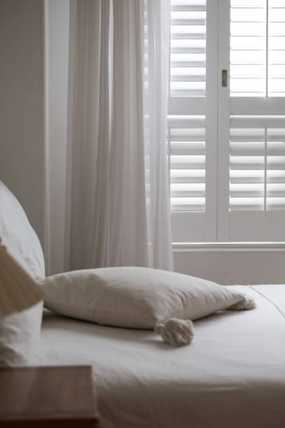 istock White themed bed sheets and white curtain, bedroom interior. 1322459100