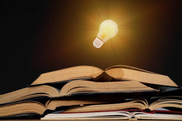 istock Light bulb and opened vintage book style vintage dark background 1322459707