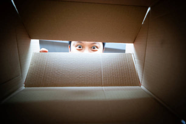 man peeking from a hole on cardboard box - brown paper imagens e fotografias de stock
