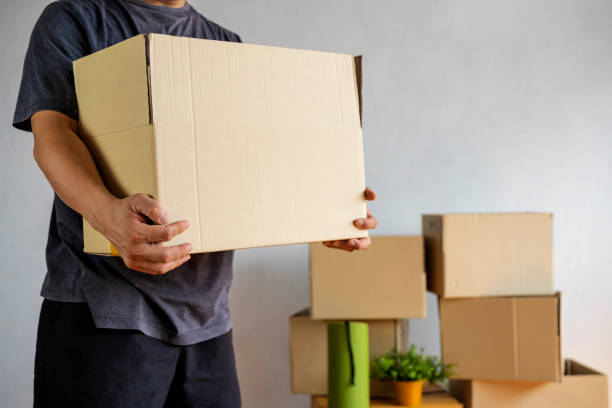 istock Midsection of man carrying open cardboard box in new home 1322459720