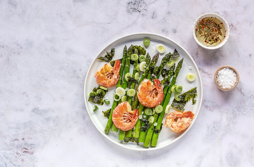 Seasonal salad from prawn shrimp, green asparagus, onion, and seaweed on a plate, festive appetizer, or buffet snack. Clean healthy eating.