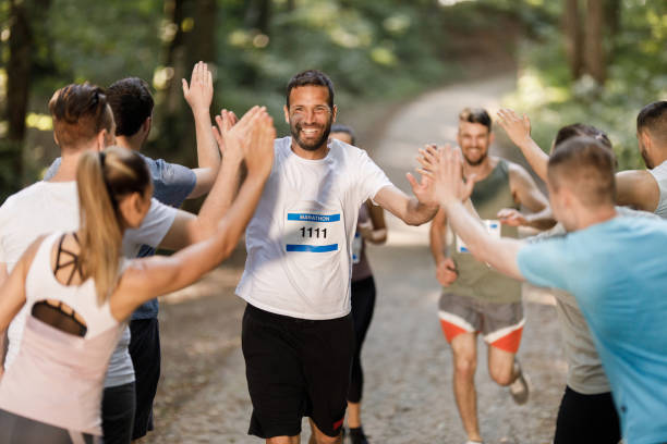 istock Happy marathon runner greeting group of athletes at finish line. 1322461392