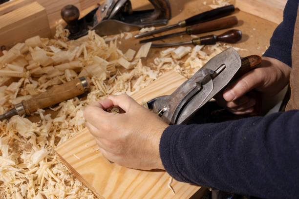 istock Close up of a Carpenter hands planing wood on a workbench at workshop 1322462245