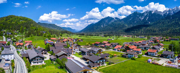 istock Wallgau Bavarian Alps. Aerial Panorama Shot. Mountains, clouds, fields, village 1322464561