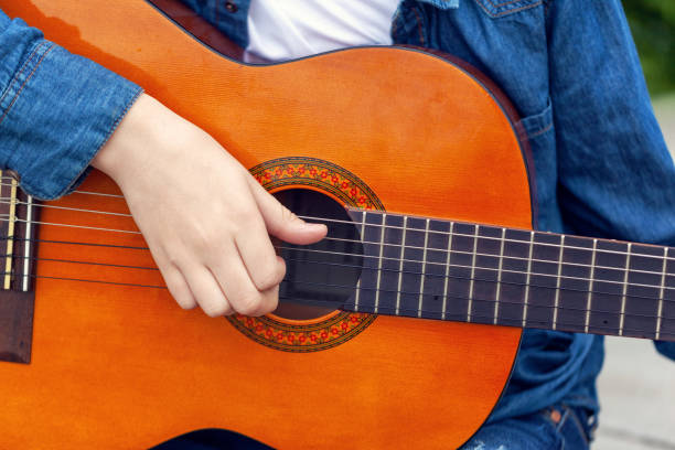 istock Young man holding a guitar and playing music. 1322464633