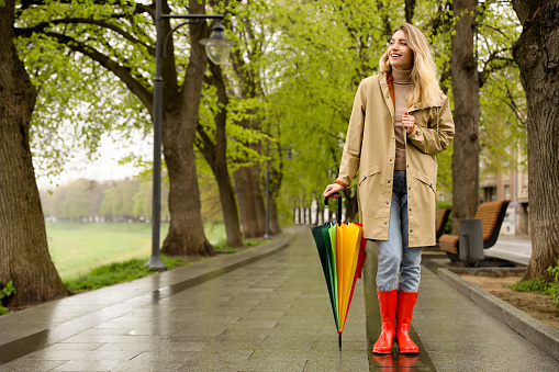 istock Young woman with umbrella walking in park on spring day 1322466622