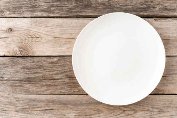 istock Overhead shot of empty white plate on rustic wooden table. Close up 1322470355