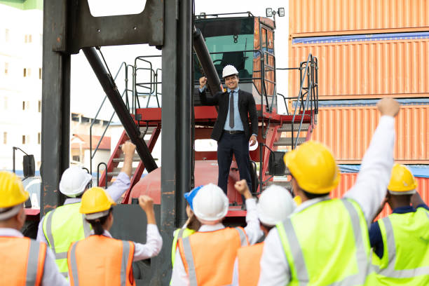 istock warehouse boss engineer standing on crane car with factory workers raise hand for congratulations in containers warehouse storage 1322471680