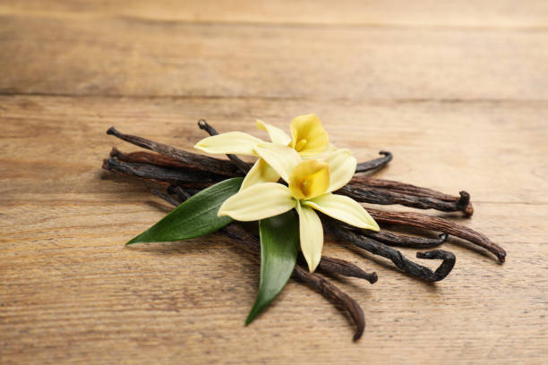 istock Beautiful vanilla flowers and sticks on wooden table, closeup 1322472349