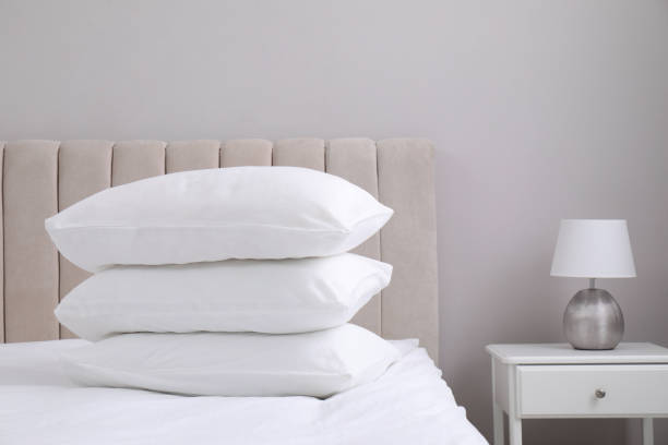 istock White soft pillows on bed and lamp in room 1322472398