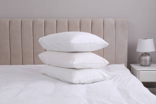 istock White soft pillows on bed and lamp in room 1322472669