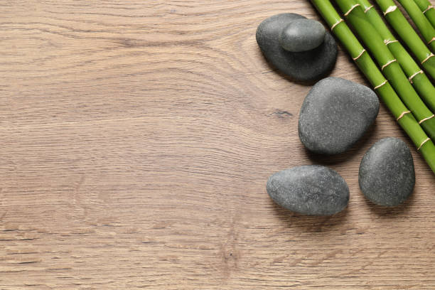 istock Spa stones and bamboo stems on wooden table, flat lay. Space for text 1322473245