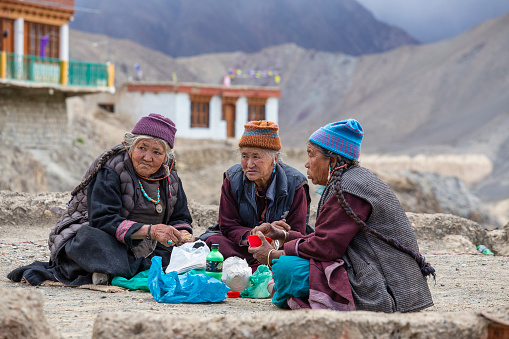 Lamayuru Gompa, Ladakh, India - june 14, 2015 : Old Buddhist people drink tea and eat food on the street next to the monastery Lamayuru in Ladakh, North India