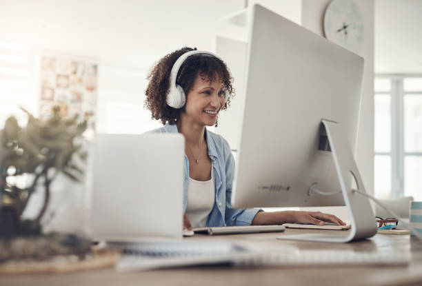 istock Shot of an attractive young woman sitting alone at home and using her computer while wearing headphones 1322485257