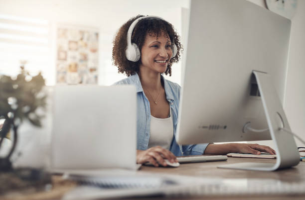 istock Shot of an attractive young woman sitting alone at home and using her computer while wearing headphones 1322485261