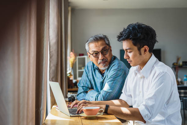 istock Asian senior father and his adult son using laptop computer while sitting at home 1322485305