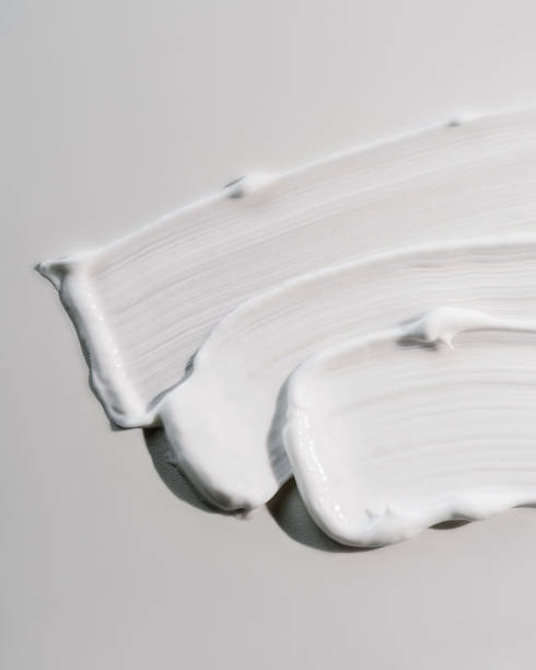 White cream texture on a white background. The texture of white cream on a white background on a round glass. Top view. lotion texture stock pictures, royalty-free photos & images