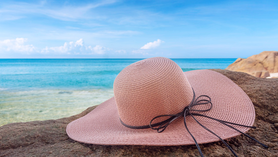 A wide-brimmed hat is placed on the beach. Summer travel concept.