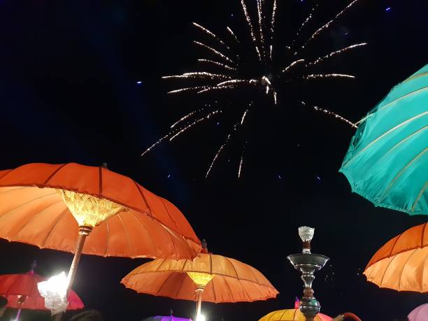istock Fireworks in the night sky and umbrella on the beach. 1322489205