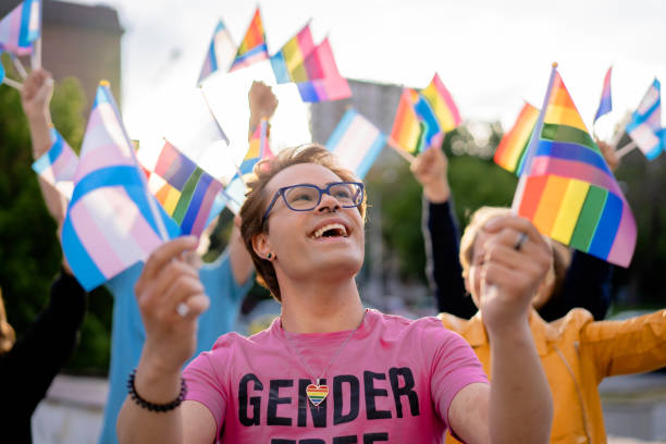 lgbtq+ aktivist hält regenbogenfahnen in den händen und blickt in den himmel - gay pride flag gay pride gay man homosexual stock-fotos und bilder