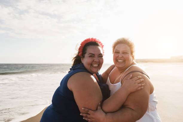 istock Plus size women friends having fun on the beach with sunset in background - Soft focus on left female face 1322490397