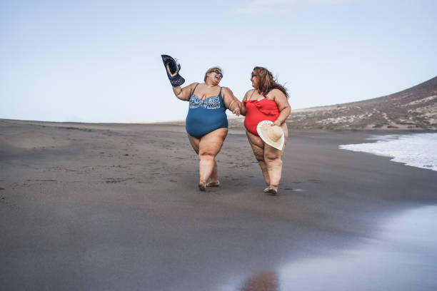 istock Plus size women walking on the beach having fun during summer vacation - Focus on faces 1322490408