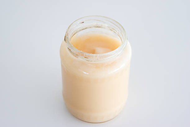 istock Jar of white crystallized rape flower honey isolated on white close up shot 1322491085